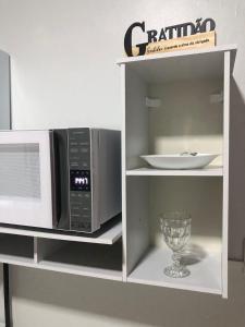 a microwave on a shelf with a wine glass at Quarto privativo 01 in Sinop