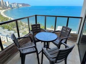 a table and chairs on a balcony with the ocean at Apartamentos cerca a la playa, Los Laureles - By Bedviajes in Santa Marta