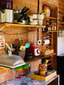 a kitchen with a brick wall with lots of pots and pans at Canoa Roots Hostel & Camping in Canoa Quebrada