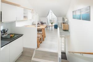 a kitchen and dining room with white cabinets and a dining table at Nordstrandperle Ap O3 in Norderney