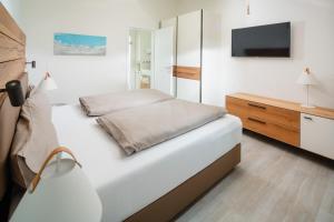a white bedroom with a bed and a tv at Nordstrandperle Ap O3 in Norderney