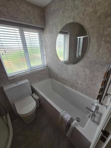 a bathroom with a tub and a toilet and a mirror at Perfect Getaway / Workstay! in Middlesbrough
