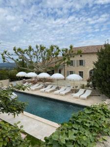 a pool with lounge chairs and umbrellas next to a building at Mas provençal d'exception in La Garde-Adhémar