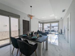 a dining room and living room with a table and chairs at Fee4Me 2 Bedroom House with Private Pool and Rooftop Terrace in Alicante