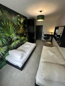 2 camas en una habitación con una planta en la pared en EasyLiving Darmstadt en Darmstadt