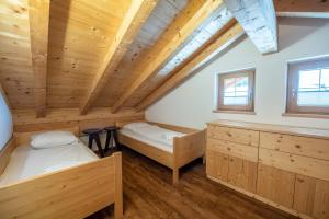 two beds in a room with wooden ceilings at Almhäuser Filzsteinalpe Almhaus 204 in Krimml