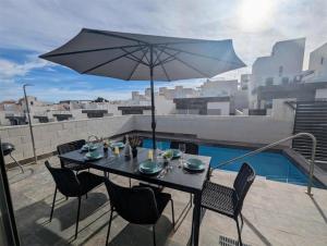 a table and chairs with an umbrella on a balcony at Fee4Me 2 Bedroom House with Private Pool and Rooftop Terrace in Alicante