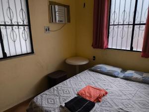 ein Schlafzimmer mit einem Bett und zwei Fenstern in der Unterkunft Quartos econômicos in Manaus