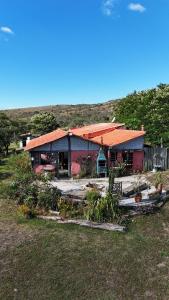 une maison avec un toit orange dans un champ dans l'établissement Sítio Mata Virgem, à Carrancas