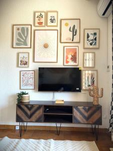 a living room with a television on a wall with framed pictures at CICADA - Wifi, Clim, Vue Mer, Parking Gratuit in La Ciotat