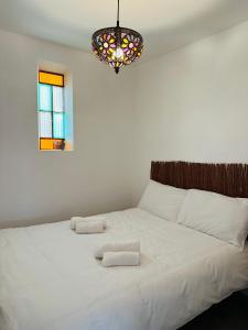 een slaapkamer met een groot wit bed en een kroonluchter bij Pool Oasis with Mountain Views in Maçanet de la Selva
