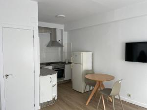 eine kleine Küche mit Tisch und Kühlschrank in der Unterkunft Apartamento acogedor en el centro de Cangas in Cangas