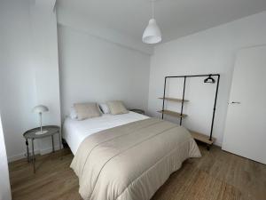 ein weißes Schlafzimmer mit einem großen Bett und einem Tisch in der Unterkunft Apartamento acogedor en el centro de Cangas in Cangas