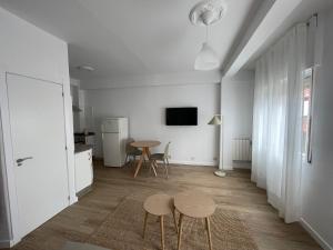 ein weißer Raum mit einem Tisch und zwei Hockern darin in der Unterkunft Apartamento acogedor en el centro de Cangas in Cangas