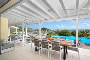 ein offenes Esszimmer mit Tisch und Stühlen und einem Pool in der Unterkunft Villa Eskarcel, vue mer sur Orient Bay, piscine chauffée, très spacieuse in Cul de Sac