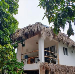 a small white house with a thatched roof at Quédate Aquí in Las Galeras