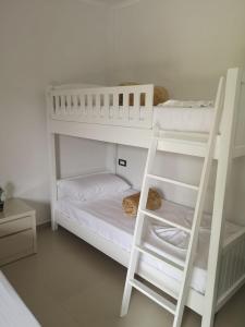 Dois beliches brancos num quarto com uma escada em Guest House Emi em Berati