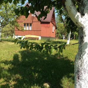 une grange rouge avec un arbre devant elle dans l'établissement Sielanka na wzgórzu, à Czostków