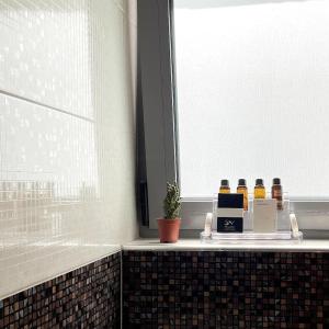 Melenia Suites في بلدة رودس: حمام مع نافذة وكاونتر عليه زجاجات