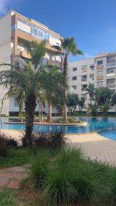 a building with palm trees in front of a swimming pool at Galia Mohammedia residence POOL WIFI in Mohammedia