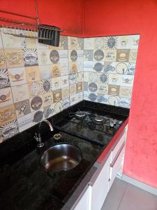 a kitchen counter with a sink and a stove at Chalés Vila Real - Tranquilidade na Serra de Carrancas - Piscina com uma vista espetacular do Pôr do Sol in Carrancas