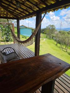 a hammock on a porch with a view of a yard at Chalés Vila Real - Tranquilidade na Serra de Carrancas - Piscina com uma vista espetacular do Pôr do Sol in Carrancas