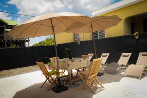 stół i krzesła z parasolem na patio w obiekcie Villa Corneille w mieście Saint-Louis