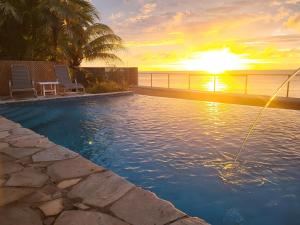 a swimming pool with two chairs and a sunset at Birdie's Nest in Black Rock