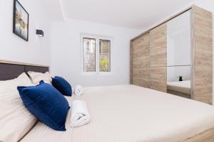 1 dormitorio con 1 cama grande con almohadas azules en Paunovic Apartments, en Tivat
