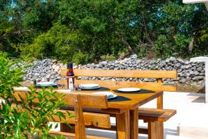 a wooden picnic table with a bottle of wine on it at Villa Lea&Robi in Unešić