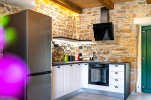 a kitchen with white cabinets and a stone wall at Villa Lea&Robi in Unešić +19 photos