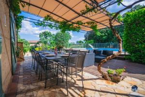 a patio with a table and chairs under a pergola at Magnifique villa provençale avec piscine et jardin in Pouzilhac