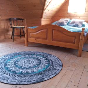 ein Schlafzimmer mit einem Bett und einem Teppich auf einem Holzboden in der Unterkunft Sielanka na wzgórzu in Czostków