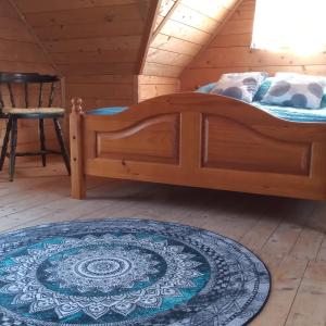 a wooden bed in a room with a rug at Sielanka na wzgórzu in Czostków