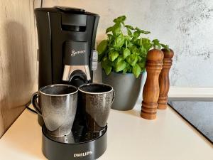 奧爾斯貝格的住宿－Ferienwohnung Augenblicke，咖啡壶和2杯柜台上的杯子