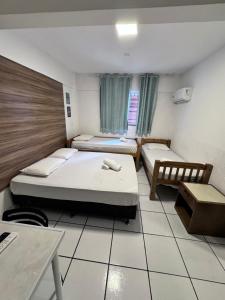 a small room with two beds and a table at Flamingo Beach Pousada in Cabo Frio