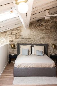 a bedroom with a bed with a stone wall at L'Etoile - Duplex cosy de 50m2 en centre-ville in Nîmes