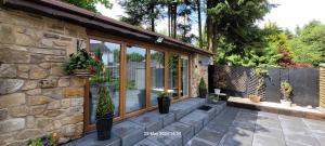 WilpshireDean Clough Lodge - Contemporary self contained studio的石头房子,设有种有盆栽植物的庭院