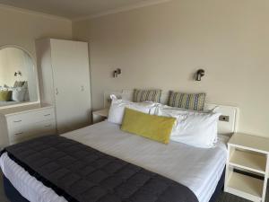 a bedroom with a large bed with a yellow pillow at Ballina Motel in Napier