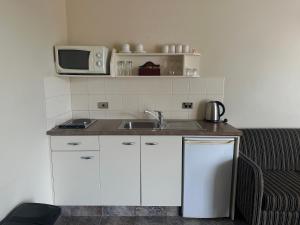 una pequeña cocina con fregadero y microondas en Ballina Motel, en Napier