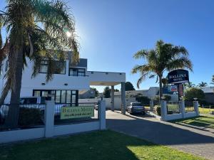 a sign in front of a building with a fence at Ballina Motel in Napier