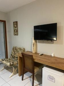 a room with a desk with a television on a wall at Serra Negra Pousada Spa in Guarapari