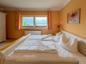ein großes weißes Bett in einem Zimmer mit Fenster in der Unterkunft Ferienhaus Seemannsruh Wohnung mit Wasserblick und abgeschlossenem Grundstück in Marienfelde