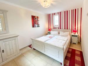 1 dormitorio con cama blanca y rayas rojas y blancas en Ferienhaus Seemannsruh Gemütliche Wohnung für Ihren Kurzaufenthalt an der Müritz, en Marienfelde