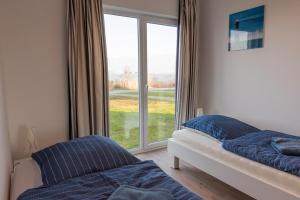 a bedroom with two beds and a large window at Ferienwohnung Schlei & Meer Olpenitz in Olpenitz
