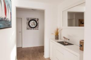 a white hallway with a clock on the wall at Ferienwohnung Schlei & Meer Olpenitz in Olpenitz +24 photos