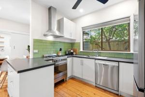 a kitchen with white cabinets and a window at Park Cottage Barwon Heads in Barwon Heads
