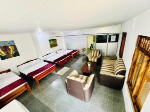 Zimmer mit 2 Betten, einem Sofa und Stühlen in der Unterkunft Jaffna Palmyrah Hotel in Jaffna