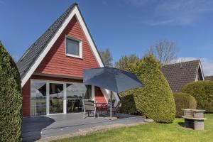 a house with two chairs and an umbrella on a porch at 50099Deichnest in Carolinensiel