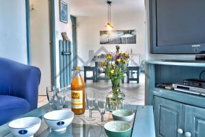 a table with glasses and a bottle and flowers on it at LocaLise - M3B - Souvenir du Guil - Maison de plain-pied avec jardin clos au Guilvinec - Tout à pied, plages, port, centre, commerces, marché - Wif inclus - Linge de lit inclus - Animaux bienvenus in Le Guilvinec